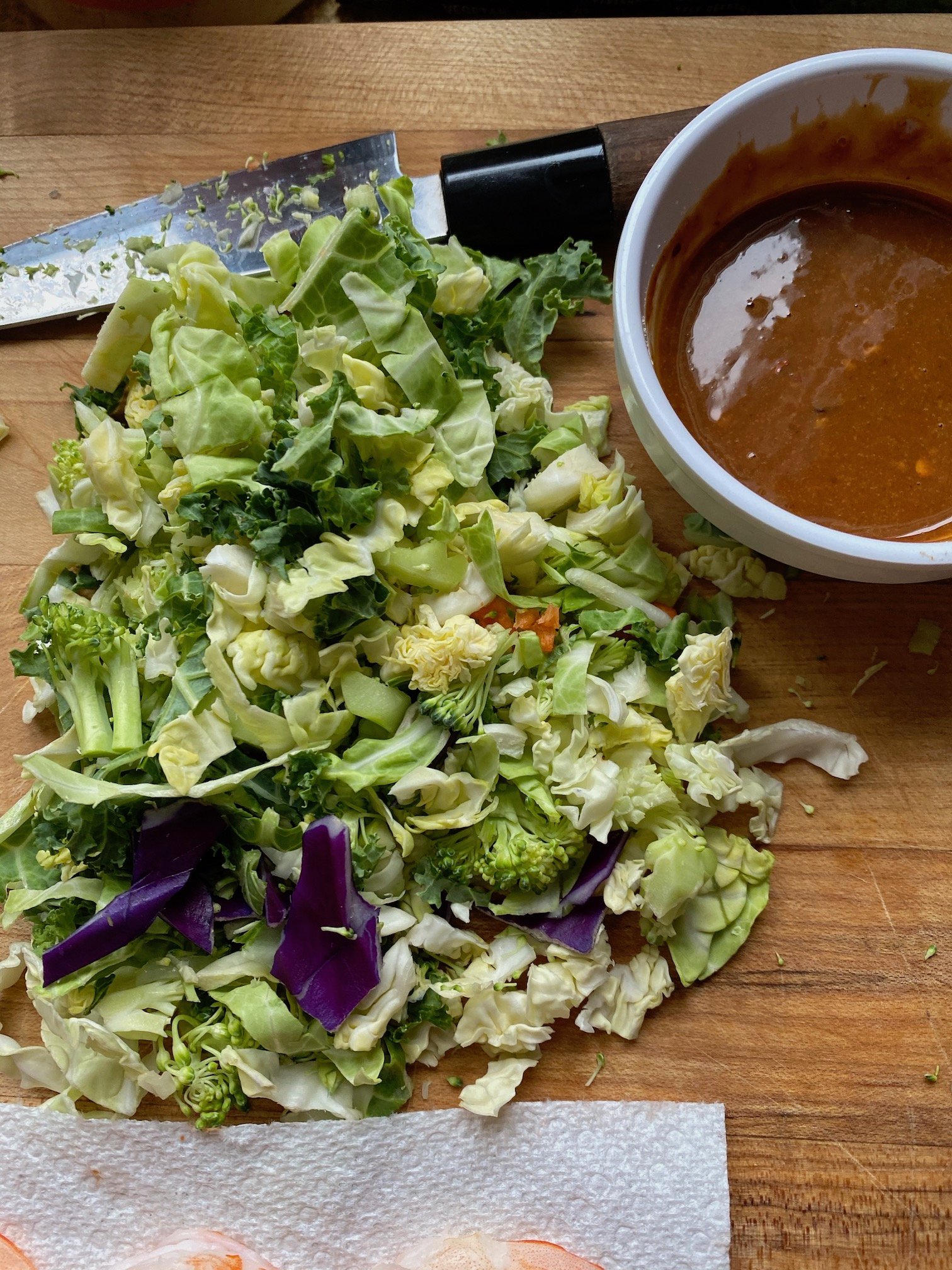 this is a cutting board with chopped bagged salad and peanut sauce for spring roll wrappers