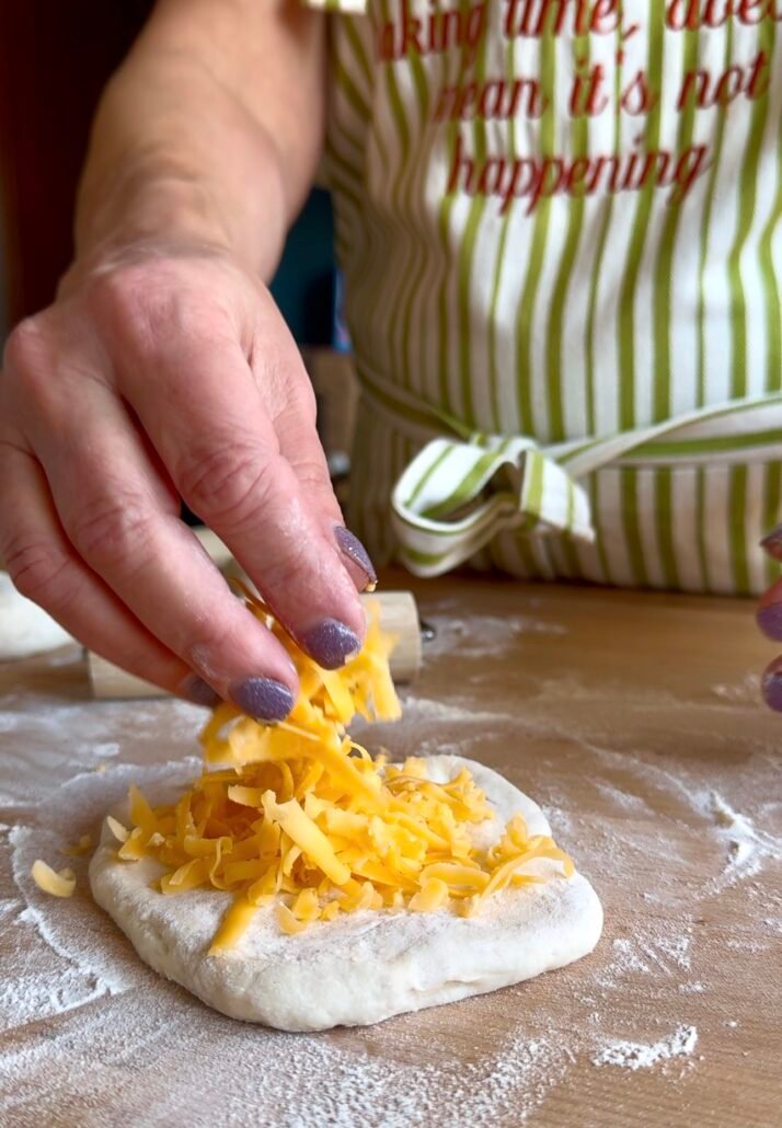 adding cheddar cheese to naan bread