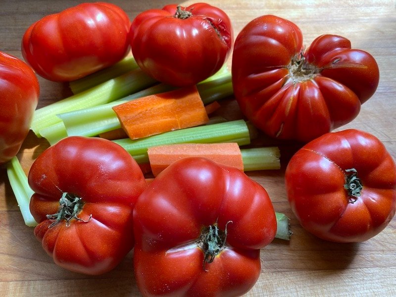 this is a picture of fresh tomatoes from a garden with carrots and celery