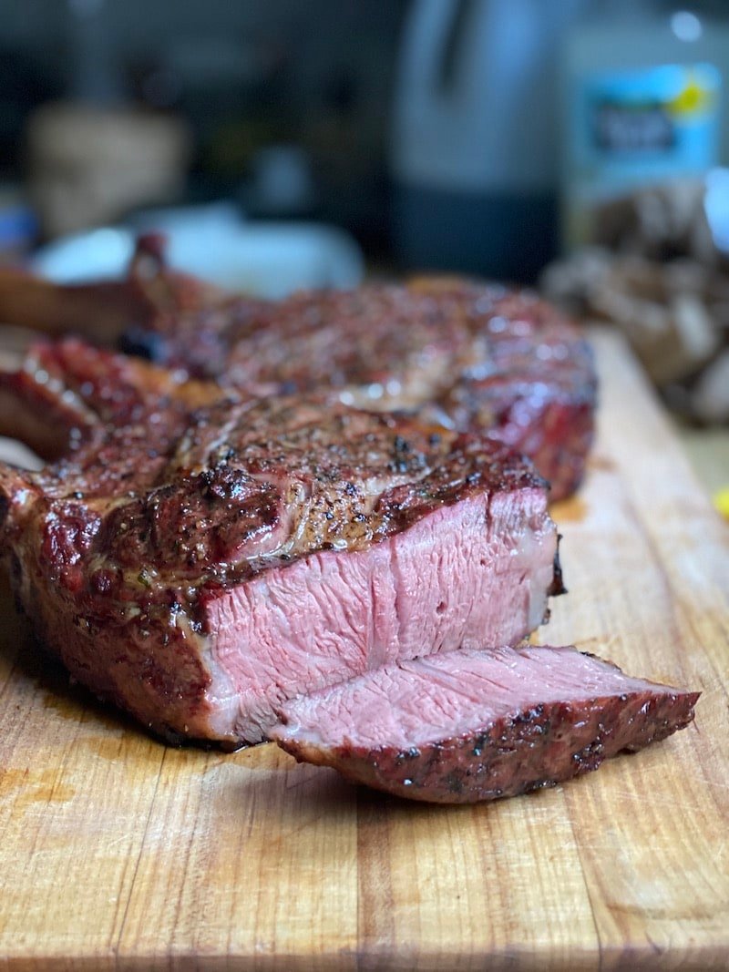 this photo is of a tomahawk steak that has been sliced open to show it is medium rare