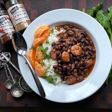 this is a bowl of black beans and sausage over white rice