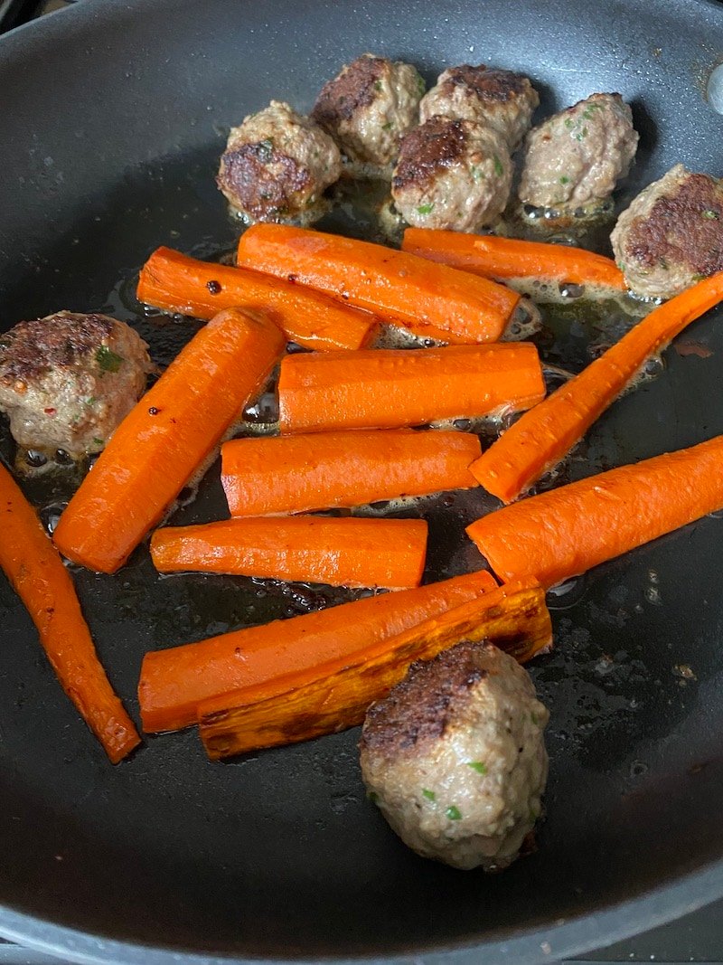 carrots and meatballs cooking in a skillet