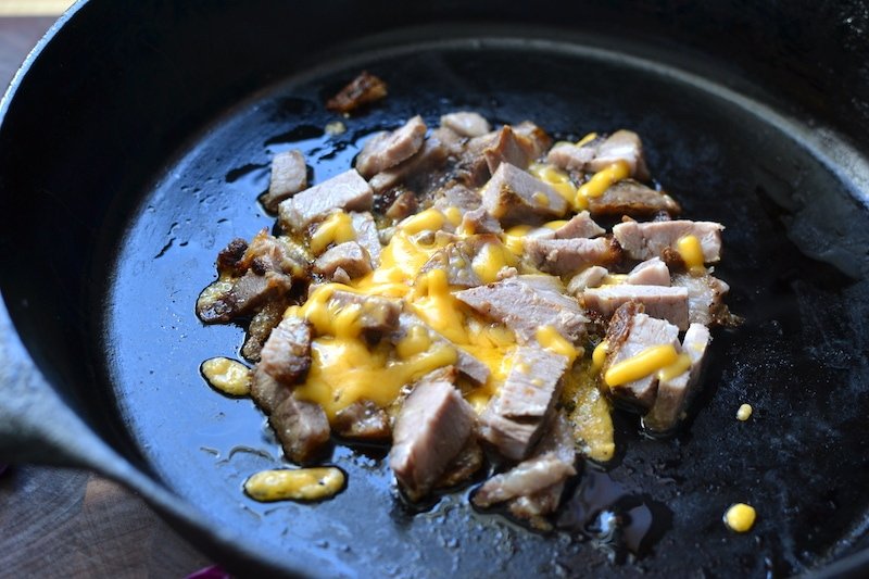 chopped pork bbq in a skillet with melted cheddar cheese