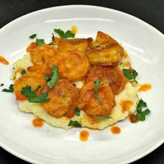 this is a plate of buffalo shrimp over grits