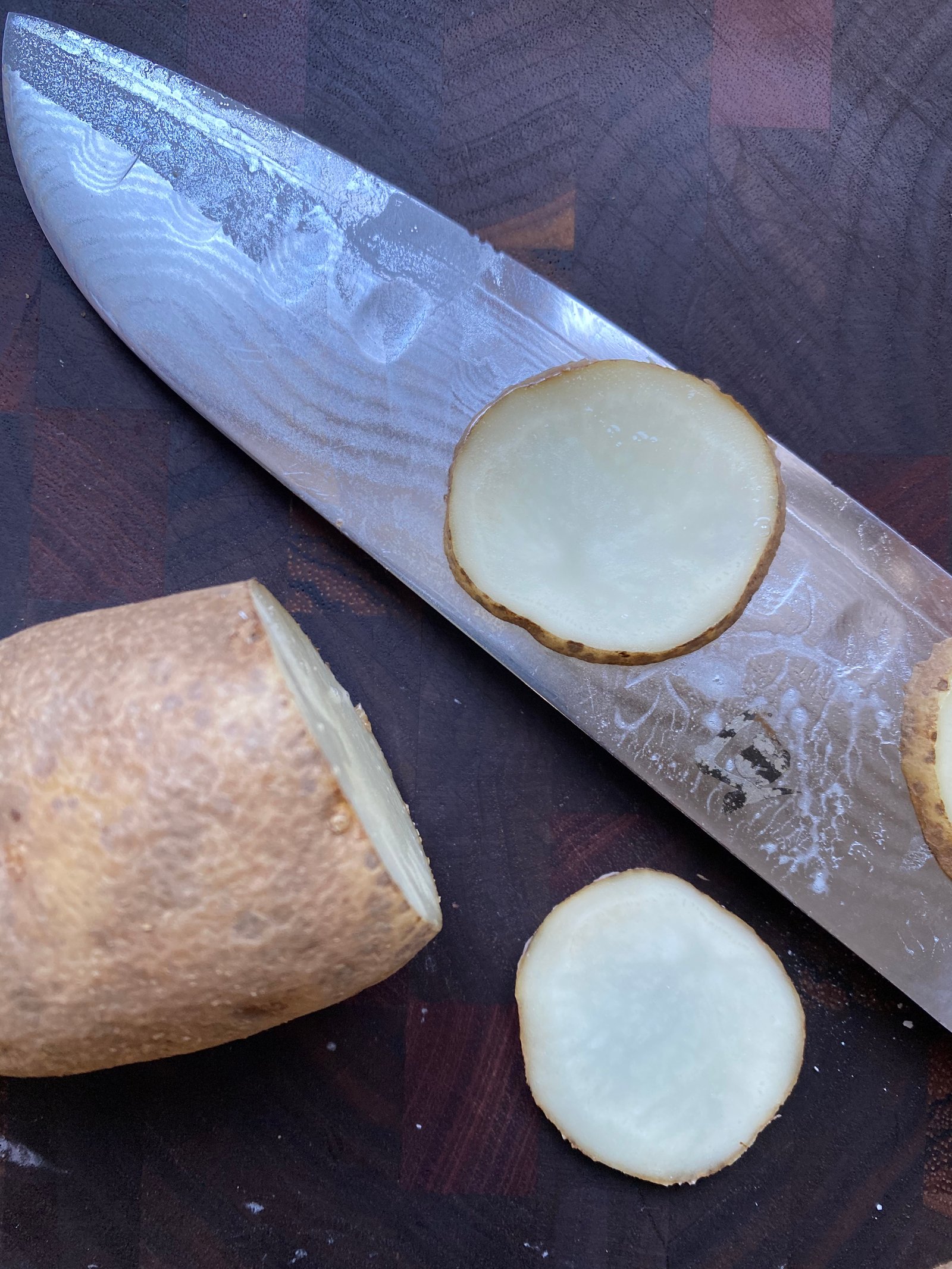 this is a photo of a knife slicing potatoes thin to make homemade potato chips