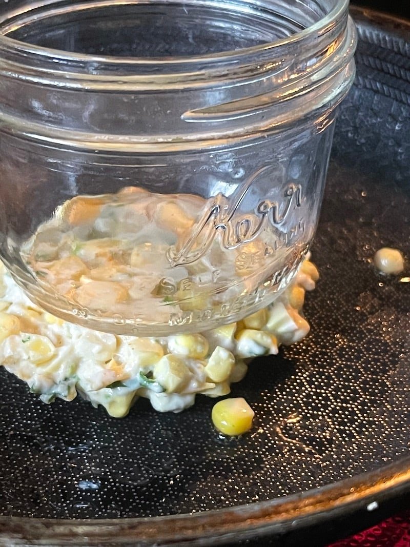 this is a photo of a mason jar pressing down a corn fritter so it cooks evenly