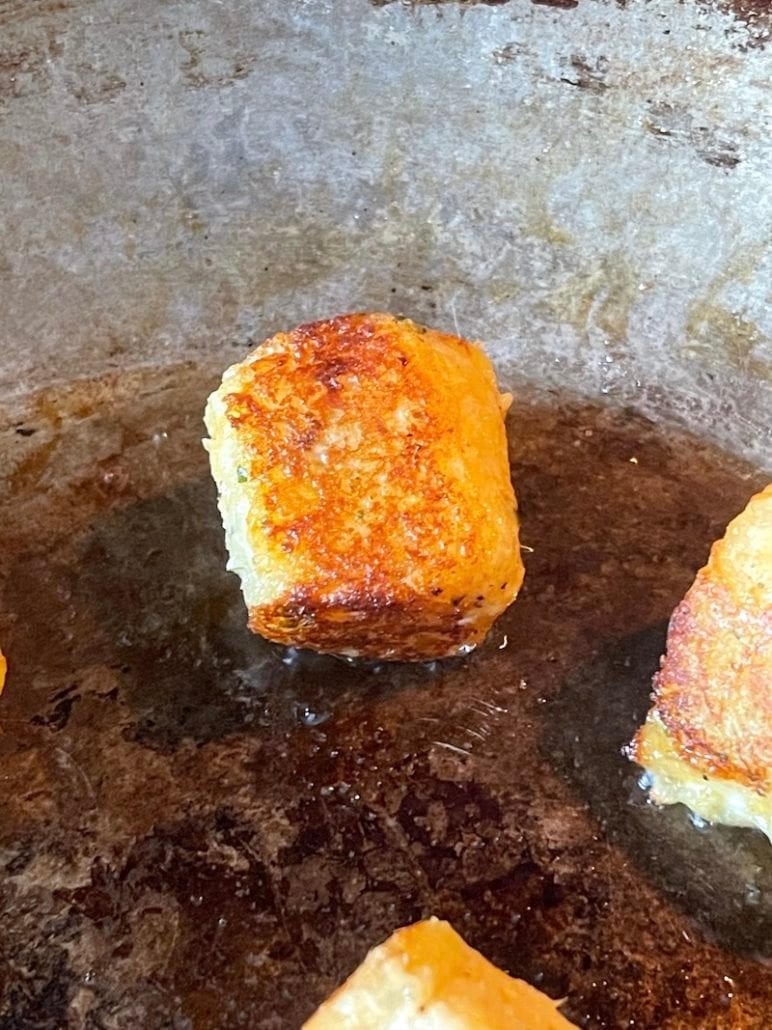 this is a photo of tater tots being pan fried in a skillet