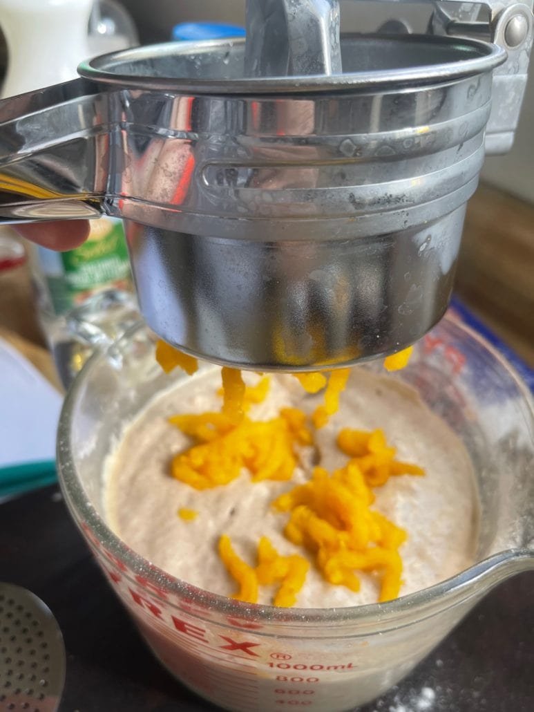 This is a photo of a potato ricer smashing cooked delicata squash