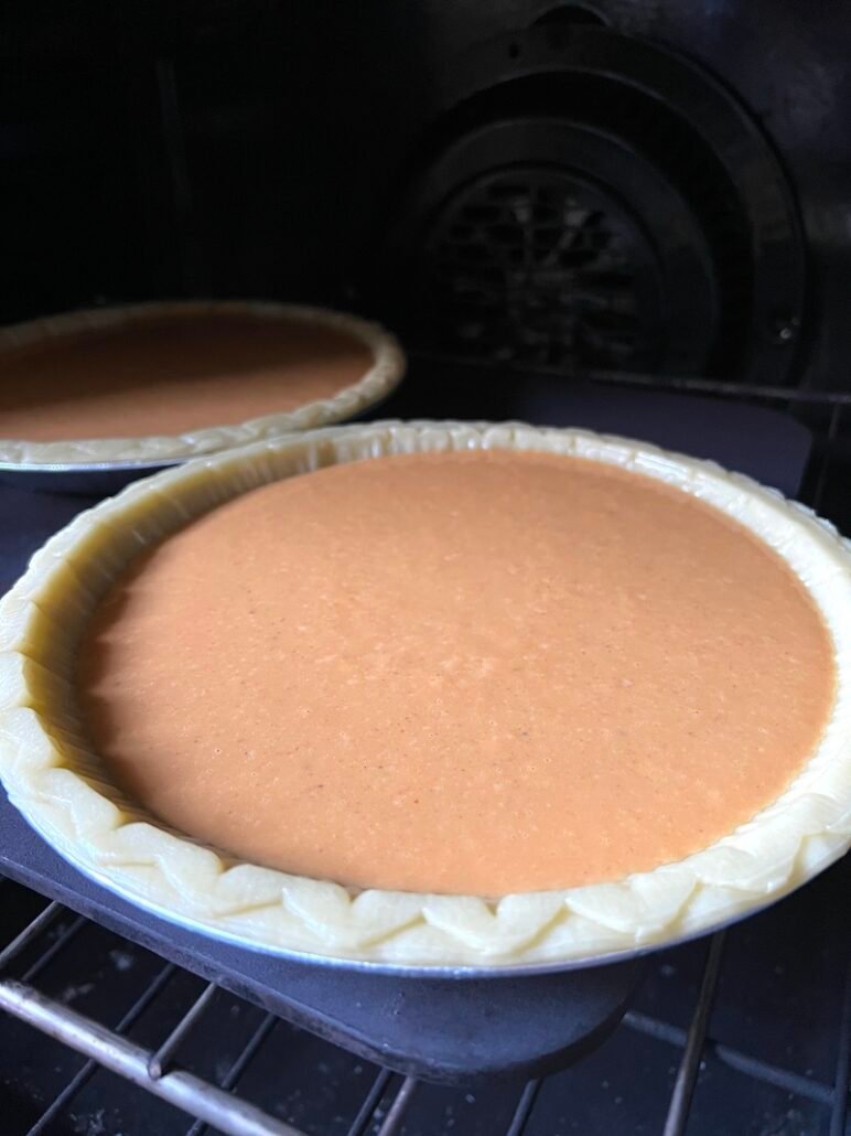 this is a photo of pumpkin pie going into the oven to cook