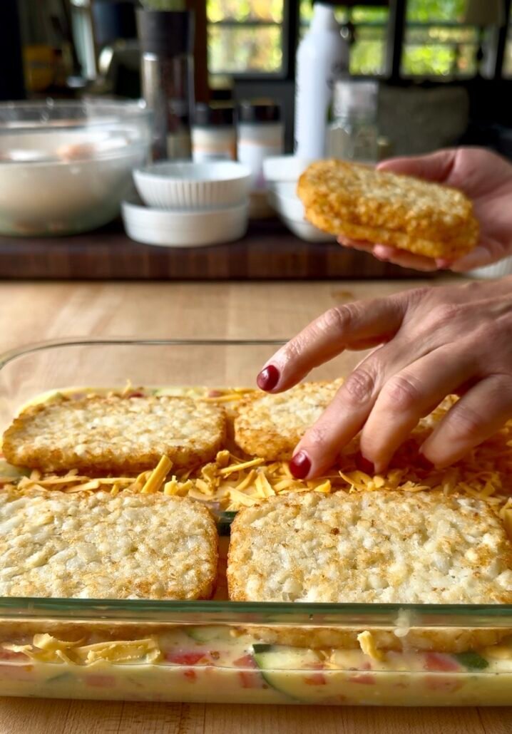 frozen hash browns being added to a breakfast casserole