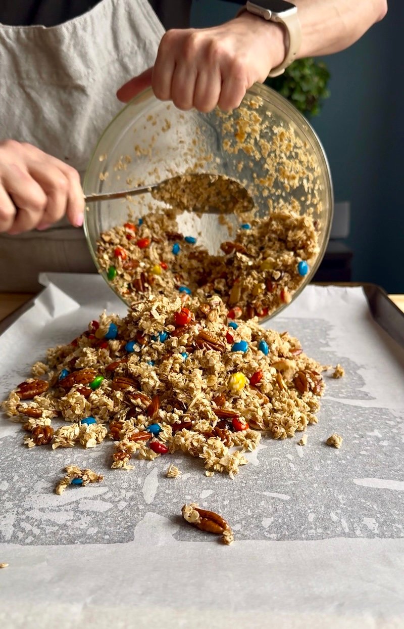 adding trail mix granola to baking sheet