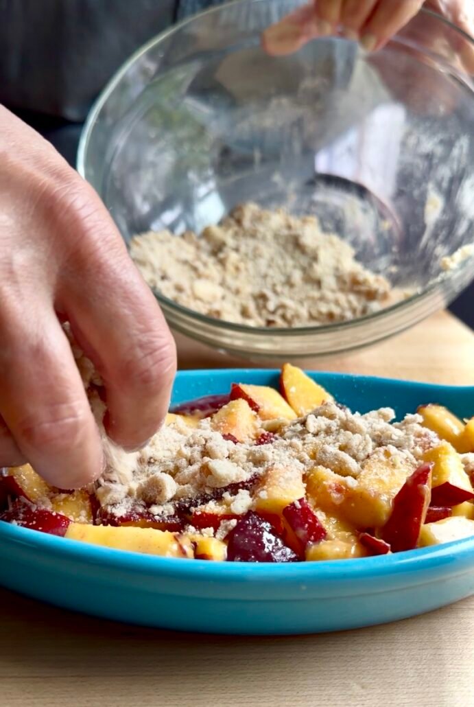 adding streusel to peach dessert