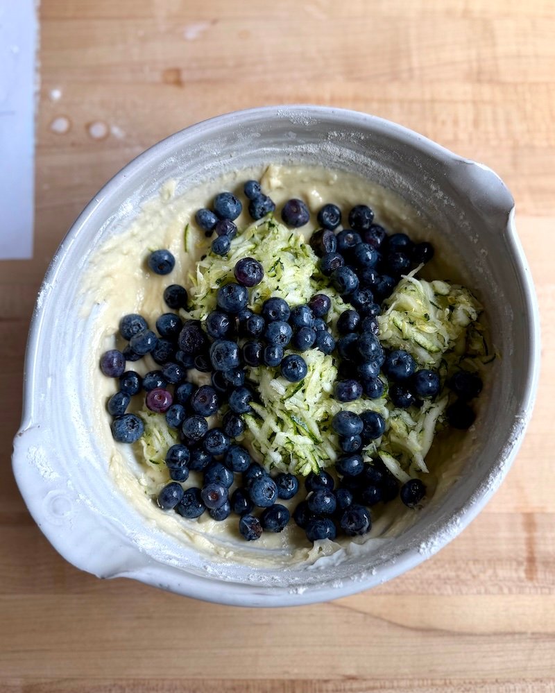 adding blueberries and zucchini to muffin batter